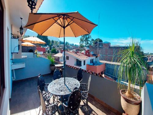 a patio with a table and an umbrella on a balcony at Hotel Suites La Fortuna in Mazamitla