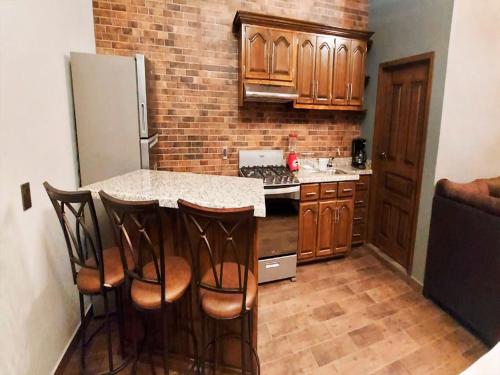 a kitchen with wooden cabinets and a kitchen island with bar stools at Hotel Suites La Fortuna in Mazamitla