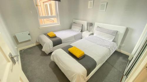 a room with two beds with yellow towels on them at Paisley Central Apartment #3 in Paisley
