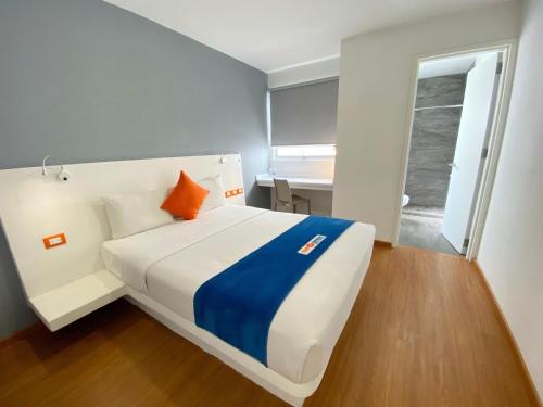 Hotel Star Express Puebla في بوبلا: غرفة نوم بسرير ابيض كبير مع وسادة برتقال