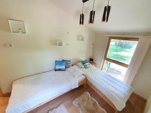 two beds in a room with a window at Bárka a Tiszához apartman in Tiszaug