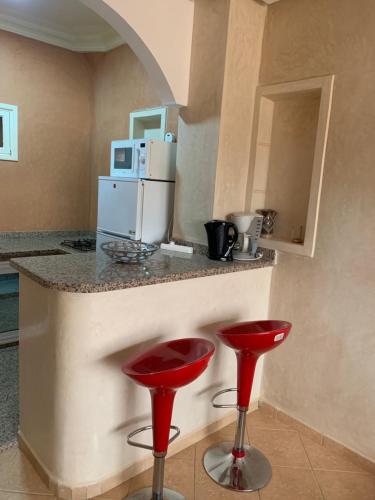 a kitchen with two red stools at a counter at Europa mirlef t aventur Guest House in Mirleft