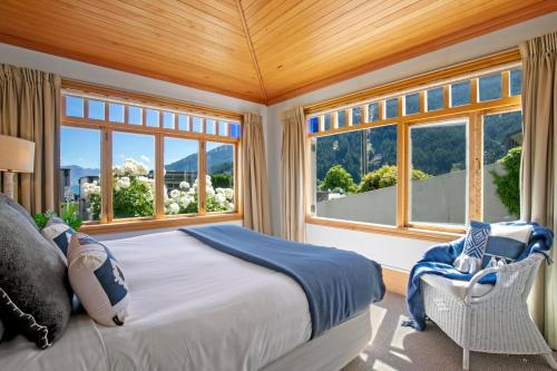 a bedroom with a large bed and windows at Historic Stonehouse & Alley Cottage - Sleeps 14 with spa pool in Queenstown