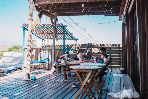 eine Gruppe von Menschen, die auf einem Deck um einen Tisch sitzen in der Unterkunft Mar de Fondo Hostel in Punta Del Diablo