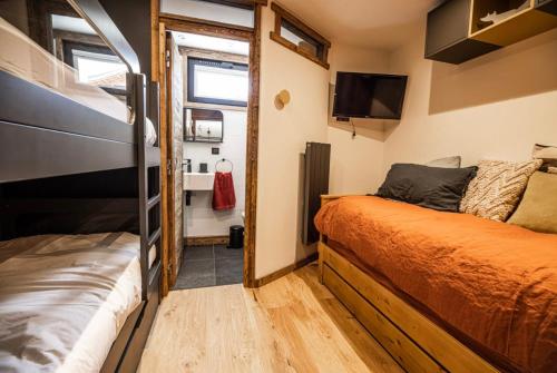 ラルプ・デュエズにあるspot, exceptl 80 m2, centre Alpe d Huez, ski au pied, Ménandière, 8 pers, 3ch, 3sdbのベッド2台とテレビが備わる小さな客室です。