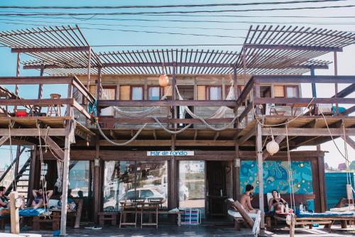 a tree house with people sitting on the beach at Mar de Fondo Hostel in Punta Del Diablo