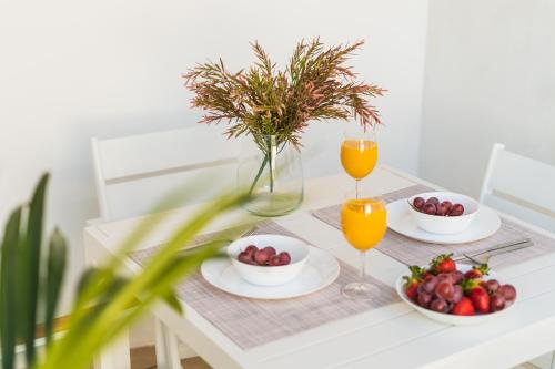 a table with plates of fruit and glasses of orange juice at Debambú Suites in Málaga