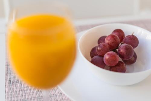 a bowl of grapes next to a glass of orange juice at Debambú Suites in Málaga