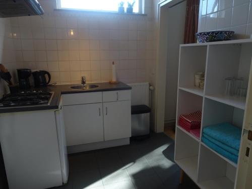 a small kitchen with a sink and a stove at Studio met woonslaapkamer,keuken en badkamer Dreefje 5 in Westkapelle