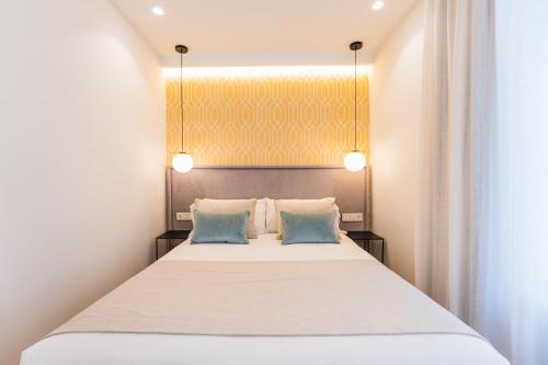 a bedroom with a large bed with two blue pillows at Debambú Suites in Málaga