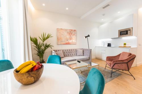 a living room with a table with a bowl of fruit on it at Debambú Suites in Málaga