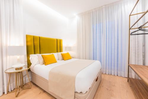 a bedroom with a large white bed with yellow pillows at Debambú Suites in Málaga
