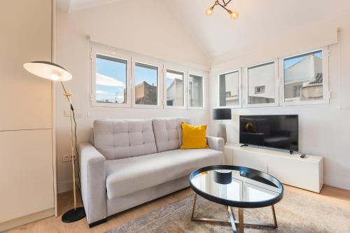 a white living room with a couch and a tv at Debambú Suites in Málaga