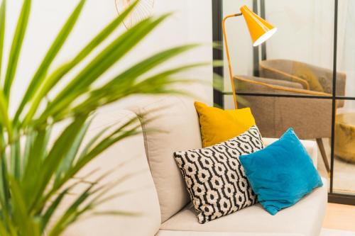 a white couch with pillows and a plant at Debambú Suites in Málaga