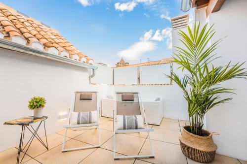 a patio with two chairs and a plant on a building at Debambú Suites in Málaga
