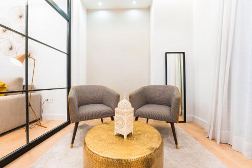 two chairs and a table in a room at Debambú Suites in Málaga