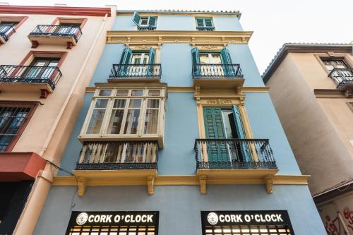 a blue building with balconies on a street at Debambú Suites in Málaga