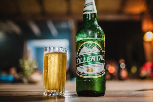 a bottle of alfalfa beer next to a glass at Mar de Fondo Hostel in Punta Del Diablo