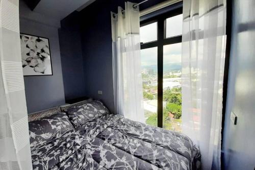a bedroom with a bed and a large window at Cebu City Apartment - Mabolo Gardens in Cebu City