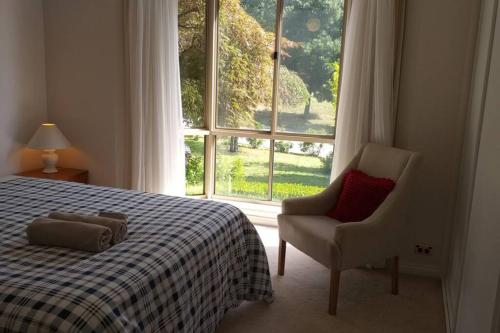 a bedroom with a bed and a chair and a window at Sweet Holiday Home by the Golf Course in Canberra