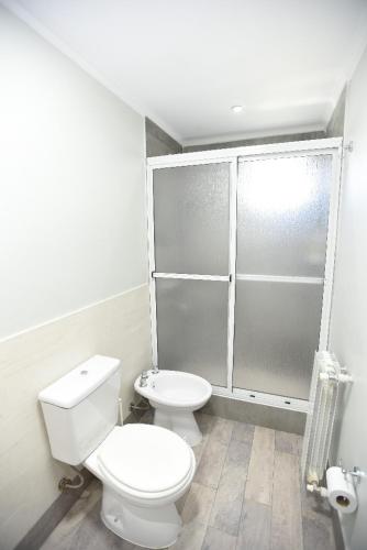 a white bathroom with a toilet and a shower at Kau Si Aike in El Chalten
