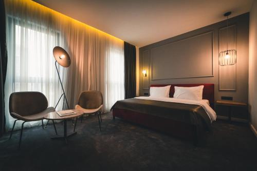 um quarto de hotel com uma cama, um candeeiro e cadeiras em Boscovich Boutique Hotel em Podgorica
