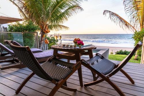 a table and chairs on a deck with the beach at Arennas Mancora in Máncora