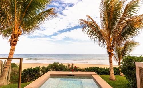 a swimming pool next to a beach with palm trees at Arennas Mancora in Máncora
