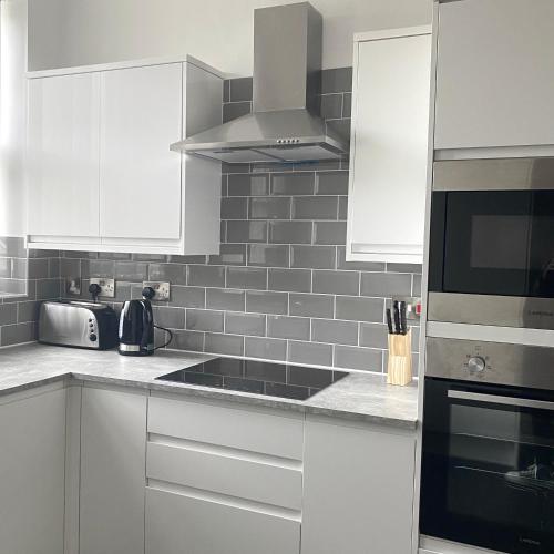 a kitchen with white cabinets and black appliances at Part St Apartments in Southport