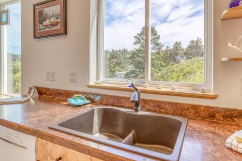 eine Küche mit einem Waschbecken und zwei Fenstern in der Unterkunft Beach Baby in Lincoln City