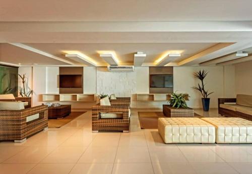 a large room with couches and tables in a building at Tabatinga Flat - Beira Mar in Conde