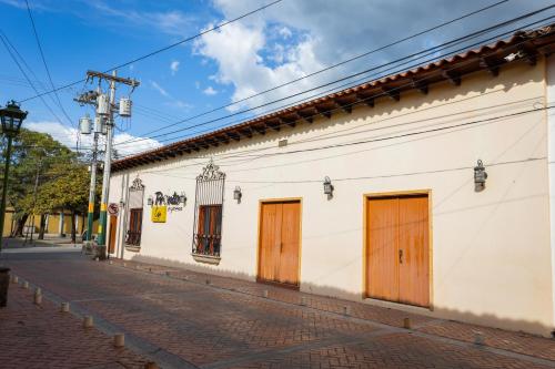 a white building with wooden doors on a street at APARTAMENTOS CASCO HISTORICO COMAYAGUA in Comayagua