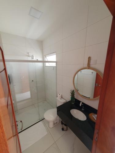 a bathroom with a sink and a toilet and a mirror at Caly Pousada in São Miguel do Gostoso