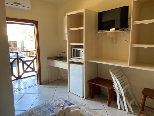 a room with a kitchen with a microwave and a table at Pousada Maré Mar in Garopaba
