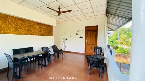 White Shore Beach Homestay في أليبي: غرفة طعام مع كراسي وطاولة ومروحة سقف