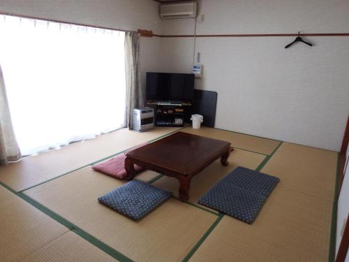 a living room with a coffee table and a tv at ペンション　メタセコイア in Aiba