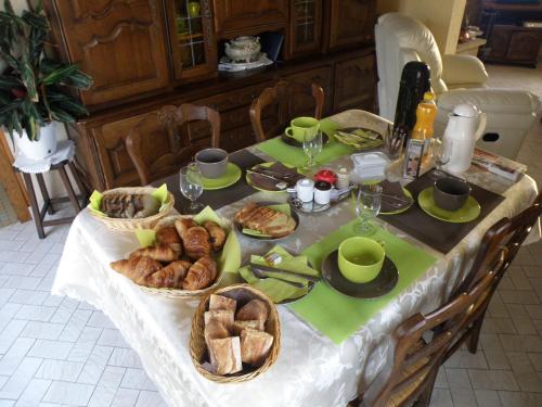 Una mesa con pan y pasteles encima. en Chambres d'Hotes Le Pavillon du Charme, en Cousances-aux-Forges