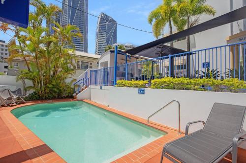 uma piscina com uma cadeira ao lado de um edifício em Surfers Beach Resort One em Gold Coast