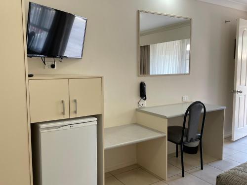 a room with a desk with a television and a chair at Crows Nest Motel in Crows Nest
