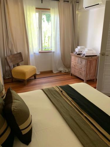 a bedroom with a bed and a chair and a window at Moorea Beach Lodge in Moorea
