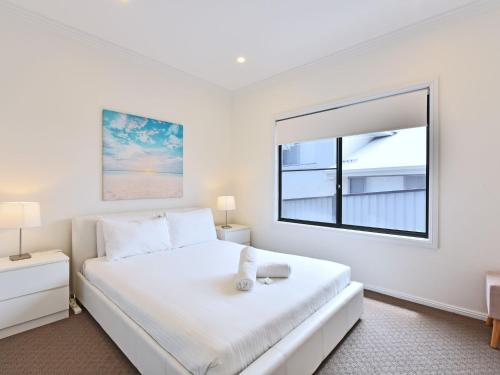 a bedroom with a large white bed and a window at Sealand Lake House Stunning Absolute Waterfront in Fishing Point