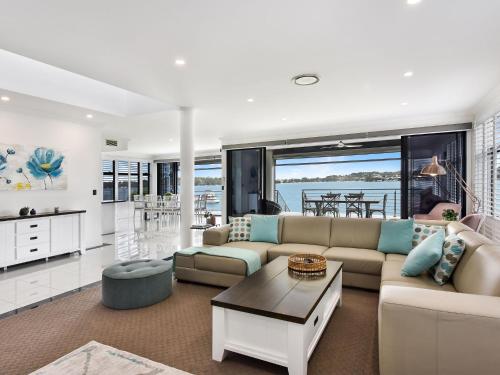 a living room with a couch and a table at Sealand Lake House Stunning Absolute Waterfront in Fishing Point