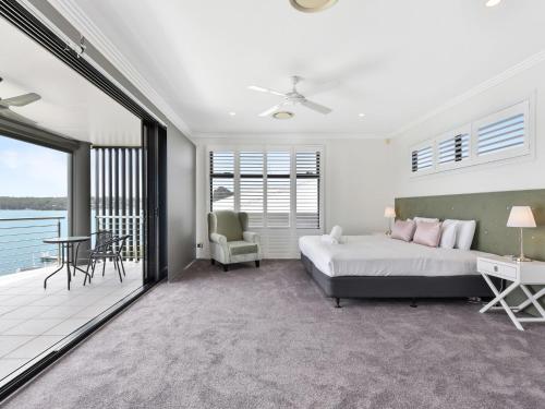a bedroom with a bed and a balcony at Sealand Lake House Stunning Absolute Waterfront in Fishing Point