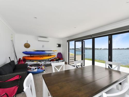 a living room with a table and chairs at Sealand Lake House Stunning Absolute Waterfront in Fishing Point