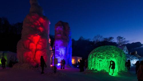 a group of people standing around an igloo in the snow at night at Sapporo's Secret Onsen Sanctuary Marukoma Onsen Ryokan in Chitose