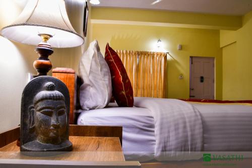 ein Schlafzimmer mit einem Bett und einer Lampe auf einem Tisch in der Unterkunft Vasathi in Madikeri