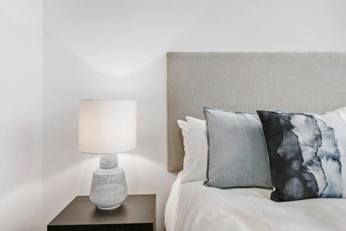 a bedroom with a bed with a lamp on a table at Melbourne City Apartments Panoramic Skyview Penthouse in Melbourne
