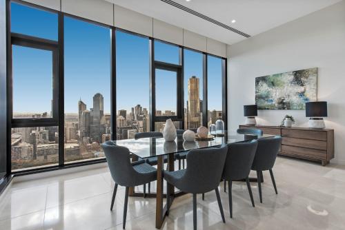 a dining room with a table and chairs and large windows at Melbourne City Apartments Panoramic Skyview Penthouse in Melbourne