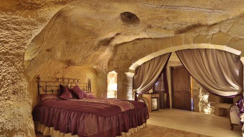 a bedroom with a bed in a stone wall at Golden Cave Suites in Urgup