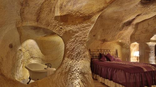 Schlafzimmer im Höhlenstil mit einem Bett und einem Waschbecken in der Unterkunft Golden Cave Suites in Ürgüp